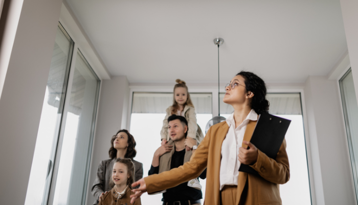 Photo of real estate agent showing a home's interior to a family of four. 