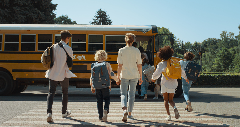 school children and parent walking toward bus
